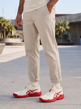 For an elevated streetwear look, opt for light-wash tapered denim jeans, an oversized cream-colored graphic t-shirt with red lettering, and a lightweight beige bomber jacket.