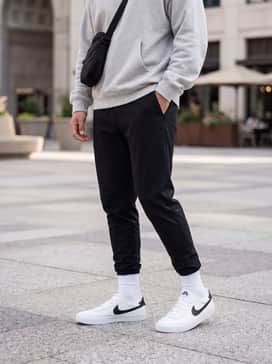 Black tapered tech joggers combined with a light grey oversized hoodie and a matching black crossbody bag for a sleek athletic-leisure aesthetic.
