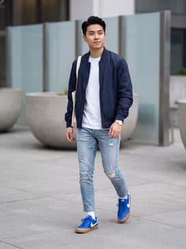 Court Shot – Distressed light-wash slim jeans, a basic white tee, and a navy blue bomber jacket for a cohesive, classic streetwear look.