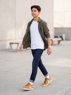 Slim-fit dark indigo denim jeans paired with a crisp white crewneck t-shirt and an unbuttoned olive green flannel shirt for a classic rugged-meets-urban look.