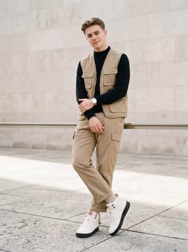 Court Vision Mid – Tan cargo pants tucked slightly into the shoe collar, styled with a black long-sleeve mock neck top and a technical utility vest.