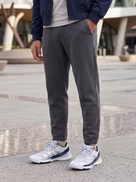 Tapered charcoal grey joggers, a plain white oversized heavyweight cotton t-shirt, and a navy blue nylon bomber jacket for a layered urban aesthetic.