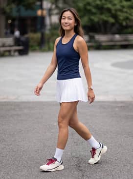 Crazyquick Lightstrike Padel Shoes – A white pleated tennis skirt paired with a navy blue moisture-wicking tank top and white crew socks for a professional court-side appearance.