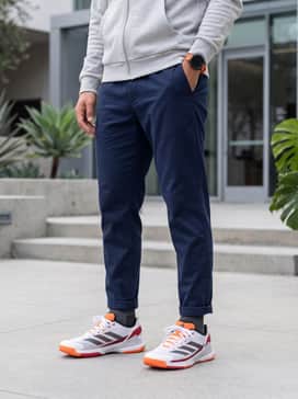 Crazyquick Padel Shoes – A modern athleisure look consisting of navy blue tapered joggers, a light grey zip-up hoodie, and a matching orange sports watch.