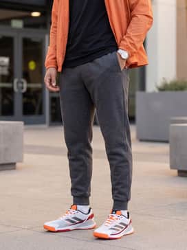Crazyquick Padel Shoes – A streetwear-inspired outfit consisting of charcoal grey tapered joggers, a black fitted compression shirt, and a lightweight orange windbreaker to play off the footwear's vibrant accents.