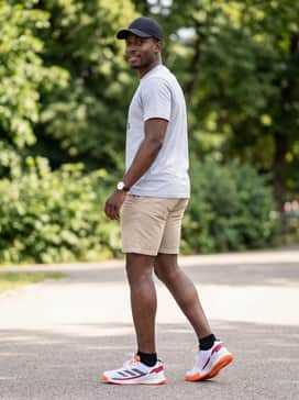 Crazyquick Padel Shoes – A summer recreational style with beige chino shorts, a light grey graphic t-shirt, and a sporty black baseball cap for a balanced, everyday athletic aesthetic.