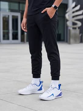 Curry 12 Team – A sleek gym ensemble pairing black tapered tech joggers with a fitted royal blue quarter-zip pullover and a silver fitness watch.