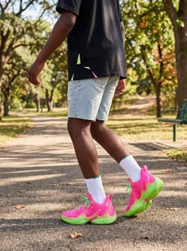 Streetwear aesthetic: Style with light-wash distressed denim shorts and an oversized black t-shirt featuring lime green accents for a trendy, bold street look.