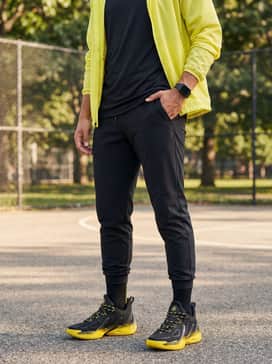 Sleek black tech-fleece joggers with a tapered ankle, a fitted black performance t-shirt, and a lightweight yellow windbreaker to match the shoe highlights.