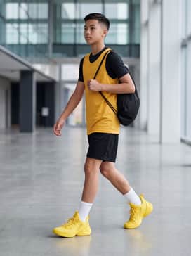 Black compression tights layered under loose black mesh basketball shorts, paired with a fitted yellow team jersey and high-performance white crew socks for a professional court presence.