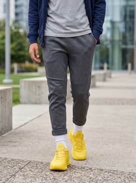 Charcoal grey tech-fleece joggers and a matching zip-up hoodie, with a vibrant yellow graphic tee underneath to pull the monochromatic footwear theme together for a cohesive athletic look.