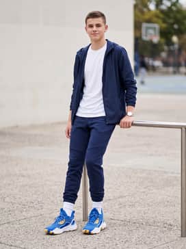 A sleek athleisure ensemble consisting of navy tech-fleece track pants, a crisp white moisture-wicking t-shirt, and a lightweight zip-up windbreaker.