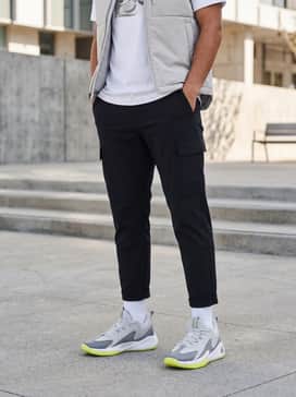 Urban streetwear: Style with tapered black cargo pants, a crisp white oversized graphic tee, and a light grey puffer vest for a layered, street-ready look.