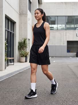 A full court-ready look featuring a black moisture-wicking basketball jersey, matching mesh shorts, and white mid-calf athletic socks to emphasize the high-contrast sneaker design.