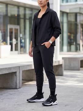 A sleek pre-game warm-up ensemble consisting of black tapered tech joggers, a fitted compression long-sleeve shirt, and an unzipped lightweight athletic windbreaker.