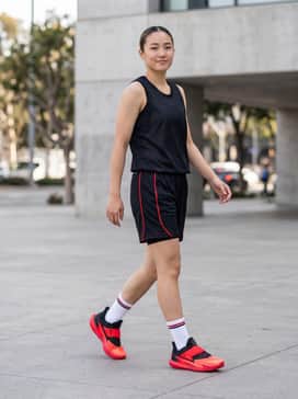 A full basketball uniform consisting of a black moisture-wicking mesh jersey and matching mid-thigh performance shorts with red side-panel piping.