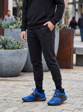 Slim-fit black joggers and a fitted charcoal hoodie to let the vibrant blue upper and speckled midsole serve as the primary visual focus.
