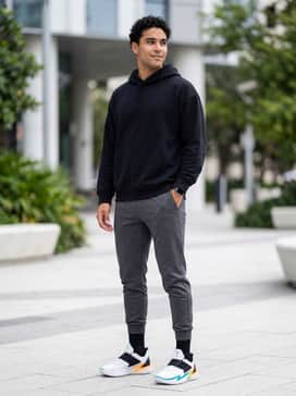 Charcoal grey tapered joggers paired with a clean black oversized hoodie and high-performance crew socks to emphasize the shoe's sleek silhouette and colorful accents.