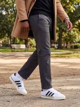 A sophisticated hybrid style using charcoal grey wool trousers, a black fine-knit turtleneck sweater, and a tailored camel overcoat to bridge the gap between formal and casual.