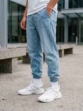 A clean streetwear ensemble with light-wash tapered denim, an oversized white graphic t-shirt, and a metallic-tone watch to complement the shoe accents.