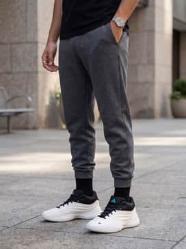 Dame X Shoes – A modern athleisure ensemble consisting of tapered charcoal tech-fleece joggers, a black fitted compression long-sleeve, and a lightweight nylon windbreaker.