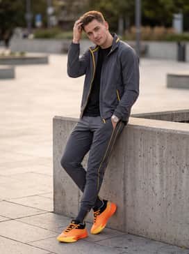 A coordinated warm-up ensemble consisting of tapered charcoal grey joggers and a technical lightweight windbreaker with yellow accents.