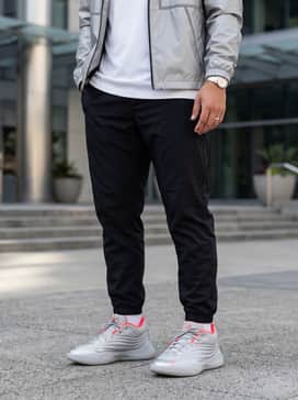 Black tapered joggers with a metallic silver windbreaker and a simple white graphic tee for a futuristic streetwear aesthetic.
