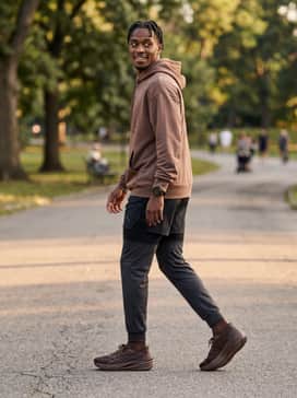A post-run athletic lounge ensemble with charcoal heather track pants and an oversized mocha-colored graphic hoodie.
