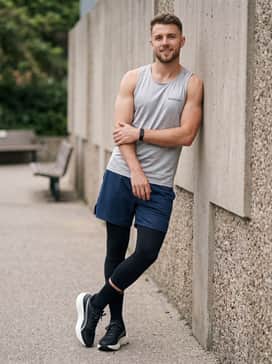 navy blue athletic shorts over black compression tights paired with a silver-toned reflective running singlet