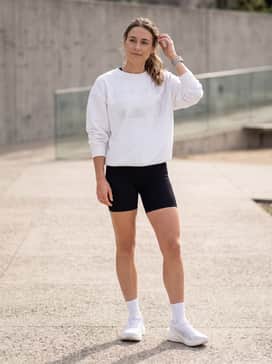 Style with a matching black ribbed biker short set and an oversized white graphic sweatshirt for a trendy post-workout 'clean girl' aesthetic.