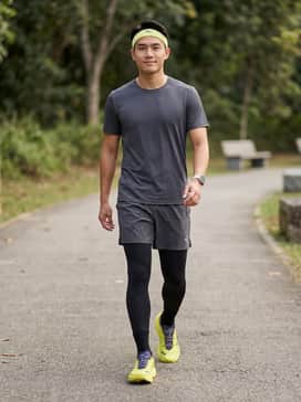 A pair of black compression running shorts paired with a charcoal grey moisture-wicking technical t-shirt and a matching lime green headband for a coordinated performance look.