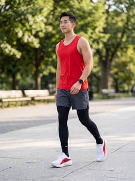 Downshifter 14 – A performance-ready running outfit featuring black compression tights, grey unlined running shorts, and a vibrant red moisture-wicking tank top to match the shoe's accents.