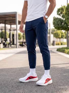 A clean gym look consisting of tapered navy blue joggers, a fitted white technical t-shirt, and high-performance white crew socks.