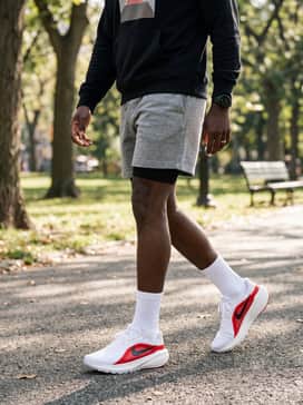 A post-training recovery style using heathered grey fleece shorts, an oversized black graphic hoodie, and a sleek sports watch.