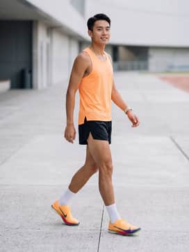 A moisture-wicking neon orange racing singlet paired with ultra-lightweight black split running shorts for a professional race-day look.