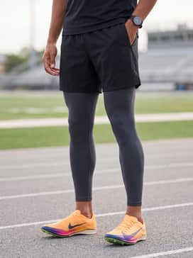 Charcoal grey compression leggings and a fitted long-sleeve technical top in a deep navy blue that complements the swoosh color.