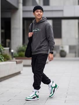 A pair of black cargo joggers with a matching green graphic hoodie and a neutral-toned beanie for a cohesive street-ready look.