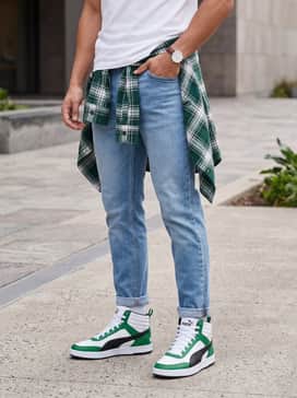 Light-wash tapered jeans paired with a crisp white t-shirt and an unbuttoned flannel shirt that features hints of forest green.
