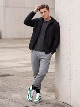Grey tech-fleece joggers and a black windbreaker jacket to create a sporty, high-performance athletic-leisure outfit.