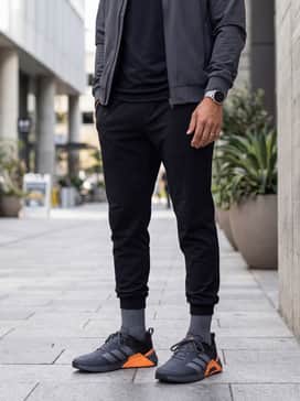 A sleek streetwear ensemble consisting of black tapered joggers, a black premium hoodie, and a slim-fit olive green bomber jacket for a layered urban aesthetic.