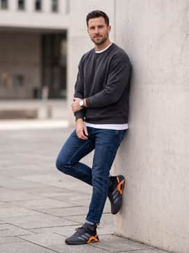 A weekend-ready outfit pairing dark-wash athletic-fit jeans with a crisp white crewneck t-shirt and an unbuttoned flannel shirt in grey and black tones.