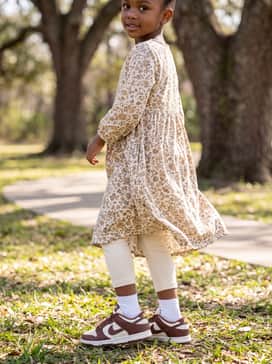 A floral-print cotton dress in muted earth tones paired with thick cream-colored leggings for a more feminine and elevated aesthetic.