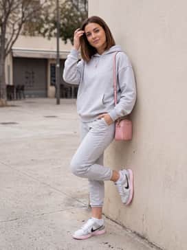 Matching light grey oversized joggers and a cropped hoodie accessorized with a small pink handbag to highlight the shoe's colorful sole.