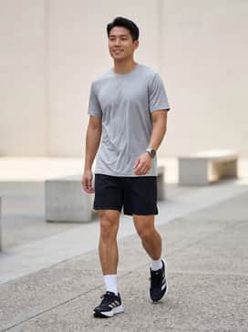 A pair of black moisture-wicking performance shorts matched with a silver-grey tech tee and low-cut white athletic socks for a classic running kit.