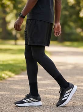 Black compression leggings layered under breathable mesh shorts and a neon-accented sleeveless training top for high-intensity gym sessions.