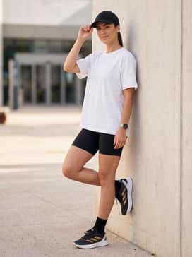 Sporty Summer Vibe: Style with black biker shorts, a white oversized graphic t-shirt, and a sleek black baseball cap for a balanced outdoor workout outfit.