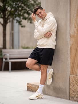 Black mesh basketball shorts worn with a vintage-wash cream graphic hoodie and mid-calf white athletic socks to emphasize the shoe's sleek profile.