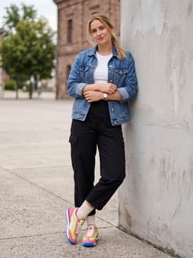 Cropped black utility trousers with a fitted white ribbed tank top and a blue denim jacket that complements the vibrant outsole.