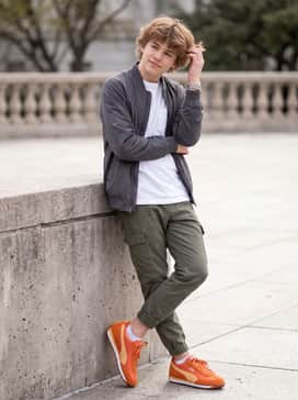 Olive green cargo pants and a white long-sleeve pocket tee, finished with a mustard yellow beanie to complement the warm orange tones.