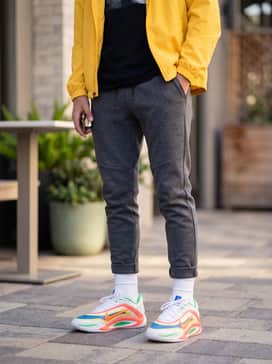 Everlasting – Charcoal grey tech-fleece joggers with a slim-fit black tee and a bright yellow windbreaker for a cohesive sporty look.